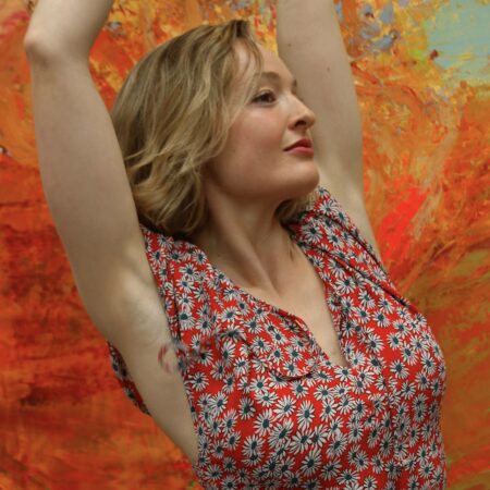 Harriet Ellis posing in a red and white printed top in front of a multicoloured wall